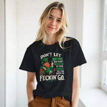 Load image into Gallery viewer, A woman wearing a black graphic t-shirt with a St. Patrick's Day design featuring a leprechaun and the text 'DON'T LET ANYONE WHO HADN'T WALKED IN YOUR SHOES TELL YOU WHERE TO FECKIN' GO.