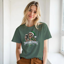 Load image into Gallery viewer, Woman wearing Irish Wolfhound Christmas T-shirt featuring a shaggy wolfhound wearing a green Santa hat and Irish tricolour scarf, holding a pint of stout with Nollaig Shona and Sláinte lettering.
